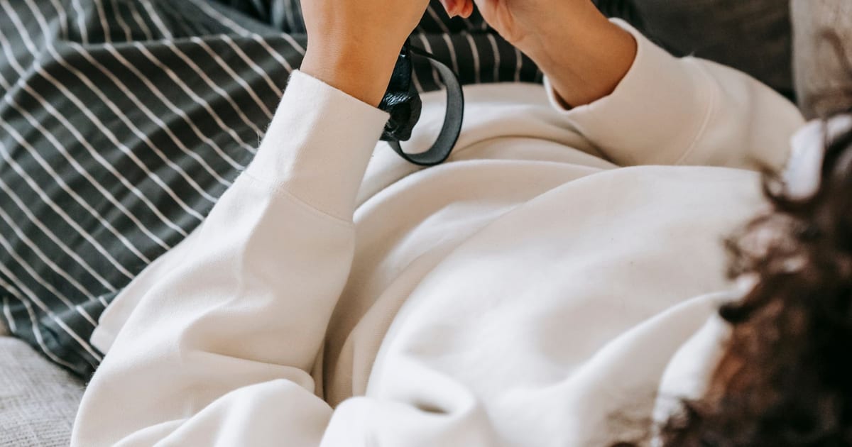A person scrolling on a phone while resting on a sofa